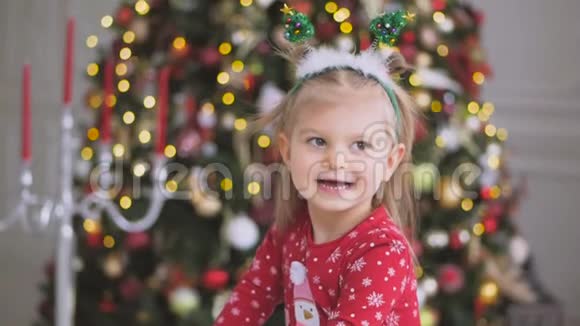站在一棵美丽的大圣诞树旁的小可爱女孩的特写镜头视频的预览图