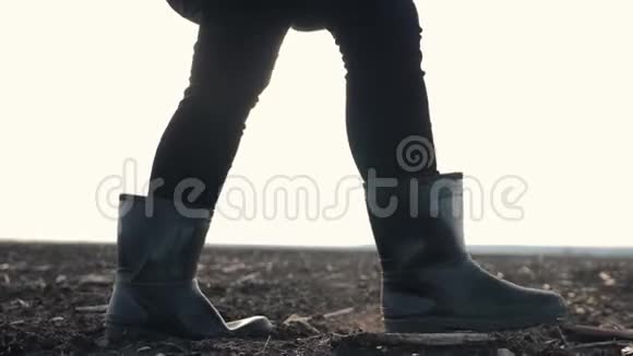 日落时分一个农民穿着橡胶靴在阳光下的一片犁地上散步农业耕作视频的预览图