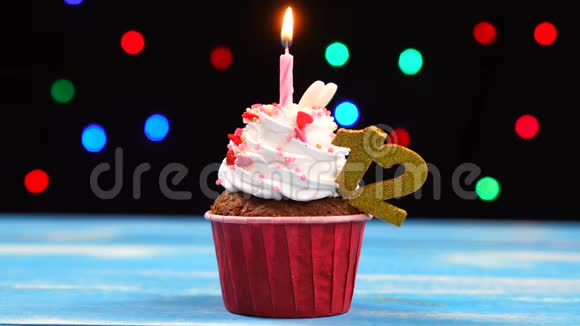 带有蜡烛的美味生日蛋糕和12号的彩色模糊灯光背景视频的预览图