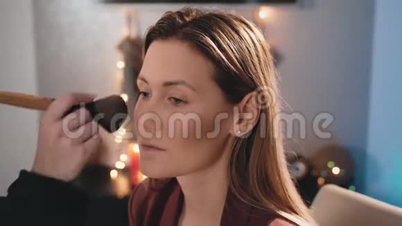 化妆师的遮阳粉和一个大刷子化妆在一个白人金发模特的脸上化妆女视频的预览图