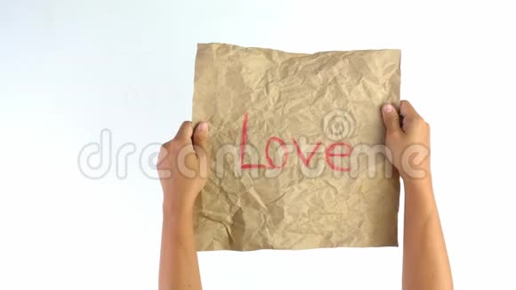 特写镜头的手皱成棕色的纸与爱的词隔在白色的背景上情感和表达观念视频的预览图