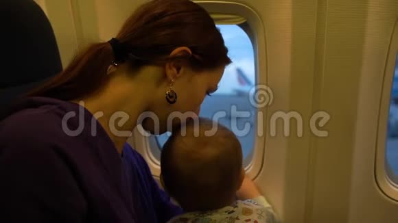 女孩和她的小儿子缓慢地看着窗外的飞机视频的预览图