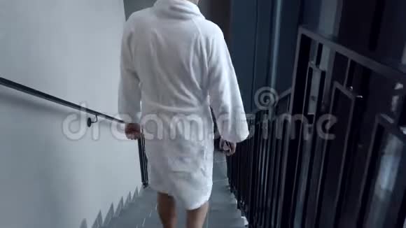 穿着浴袍和拖鞋的男人从酒店楼梯下来视频的预览图
