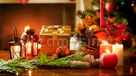 特写4k镜头用木桌上的蜡烛装饰品和礼物在圣诞树和壁炉上直播视频的预览图