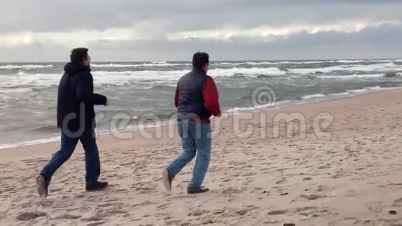 两个中年男人一起在沙滩上奔跑视频的预览图