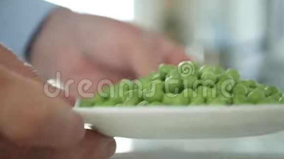 厨房里的男人提供一个充满新鲜和甜蜜的绿色豌豆的盘子视频的预览图