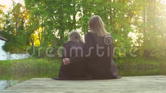 女人和她的女儿坐在池塘附近视频的预览图