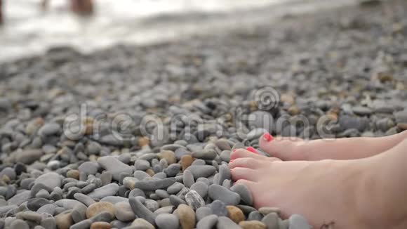 女人脚踩在鹅卵石滩上光滑的卵石上视频的预览图