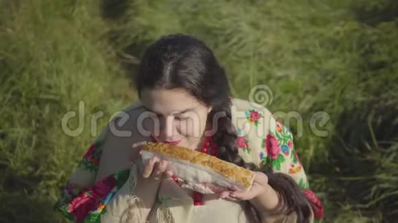 坐在草地上嗅着美味猪油准备吃的胖女人的画像传统观念视频的预览图