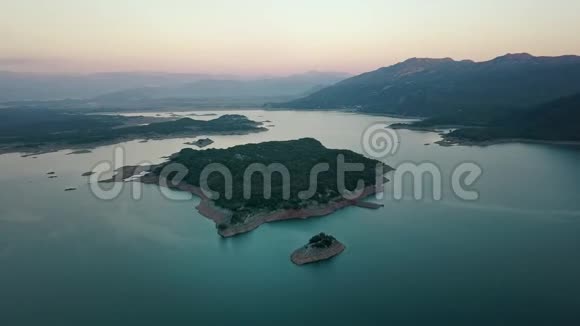 欣赏美丽的湖景岛在中间日落时黑山的无人机飞行4K分辨率视频的预览图