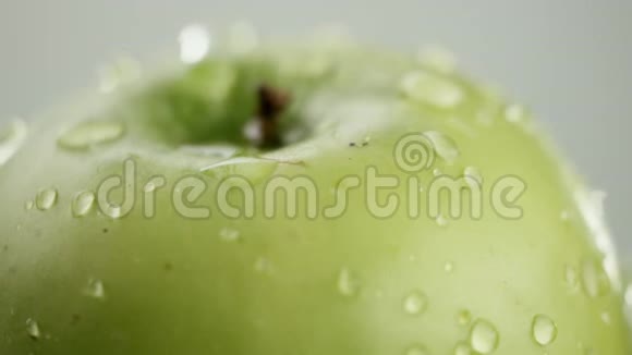 在视频中我们看到一个绿色的苹果水开始从顶部倾泻就像淋浴白色背景特写视频的预览图
