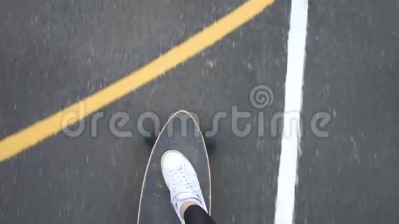 女孩骑在柏油路上的滑板上骑在草地上视频的预览图
