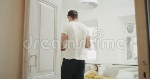 年轻人把早餐带给他的女朋友完美的早晨在舒适的卧室视频的预览图