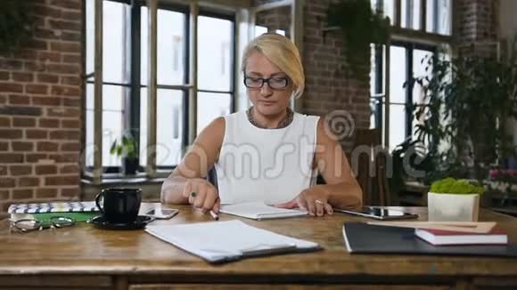 一位长相迷人头痛的白种人妇女完成了在办公桌前的工作并摘下了眼镜视频的预览图