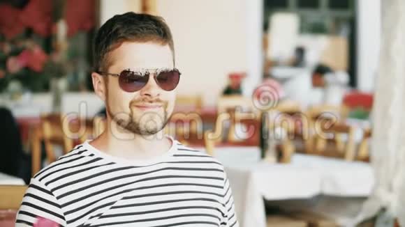 一个留胡子的年轻人度假时在街头咖啡馆喝咖啡视频的预览图