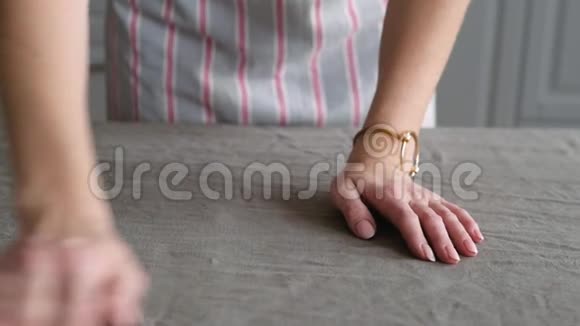 女人的手在桌子上铺上灰色的桌布为家人提供晚餐视频的预览图