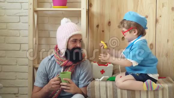 父亲和孩子在玩父子俩在一起时都在微笑打扮成医生的男孩在玩爸爸视频的预览图