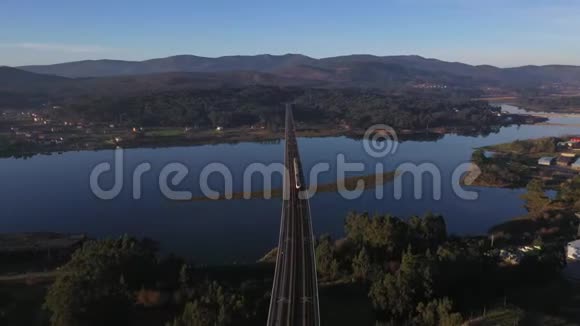 火车从无人驾驶飞机穿过大桥在河的顶部拍摄视频的预览图