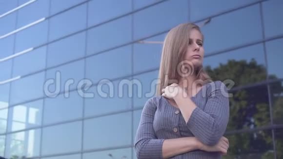 可爱的年轻女孩在城市环境中行走一个穿灰色裙子的快乐女孩在一栋玻璃建筑附近视频的预览图