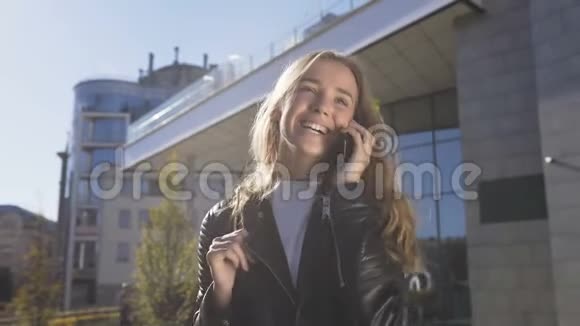 一幅美丽的年轻女子的肖像正走在城市的街道上同时与她的朋友在智能手机上交谈很漂亮视频的预览图