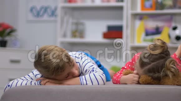微笑的孩子躺在沙发上看着相机兄弟姐妹的友谊视频的预览图