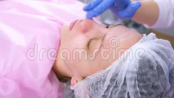 美容师把润肤霜涂在女人脸上特写的脸视频的预览图
