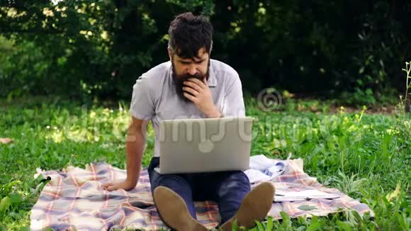 有电脑的快乐男人夏天在公园里用笔记本电脑的帅哥移动办公概念视频的预览图
