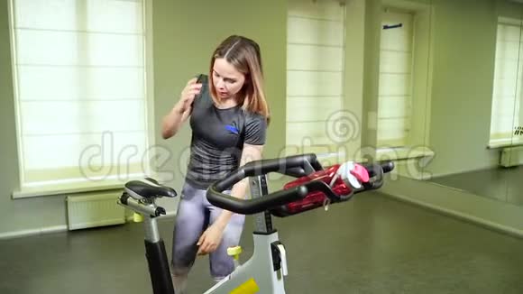 年轻女子在有氧训练前准备运动自行车视频的预览图