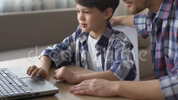父亲帮助儿子做笔记本电脑作业接受现代技术教育视频的预览图