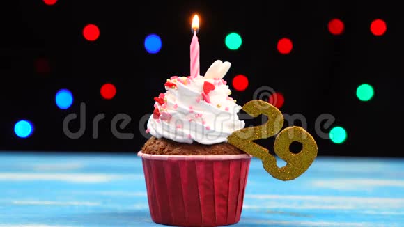 带有蜡烛的美味生日蛋糕和29号的彩色模糊灯光背景视频的预览图
