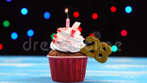 带有蜡烛的美味生日蛋糕和28号的彩色模糊灯光背景视频的预览图