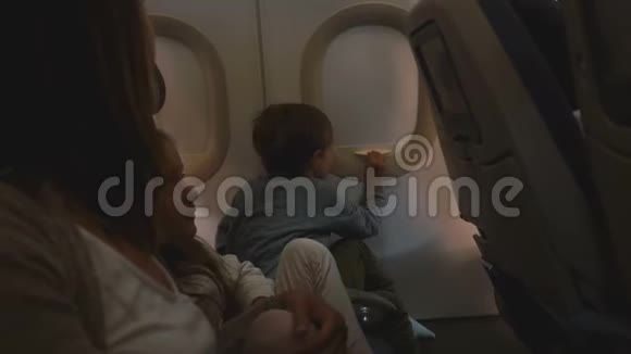 快乐好奇的小男孩在飞行中打开飞机窗盖享受与家人一起度假的风景视频的预览图