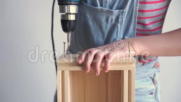 女人做一件非女人的工作用螺丝刀在木箱里钻一个洞动作缓慢视频的预览图