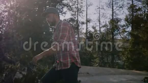 镜头跟随年轻快乐的当地男子穿着格子衬衫独自徒步在美丽的约塞米蒂国家森林慢动作视频的预览图