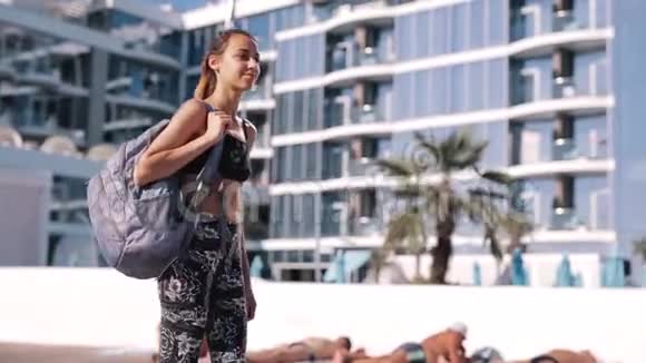美丽苗条的年轻女子穿着运动服在海岸与水疗酒店快乐的女性性感的晒黑身体完美视频的预览图