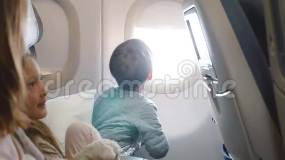 快乐的小男孩在和家人一起去度假旅行时从飞机的窗口座位上欣赏风景视频的预览图