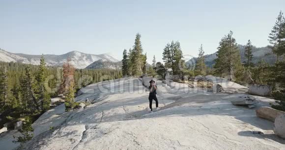 无人机拍摄的年轻女子与专业相机在惊人的山景在约塞米蒂国家公园视频的预览图