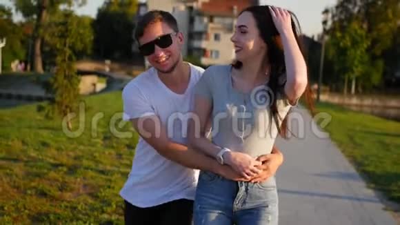 年轻快乐的可爱夫妇在夏天在公园里玩玩愚弄温暖的晴天中弹视频的预览图