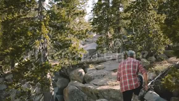后景年轻人穿着格子衬衫徒步旅行在美丽的约塞米蒂国家公园缓慢运动的白色岩石攀爬视频的预览图