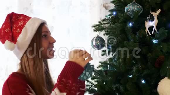 圣诞老人帽中快乐的年轻女子用包装饰圣诞树视频的预览图