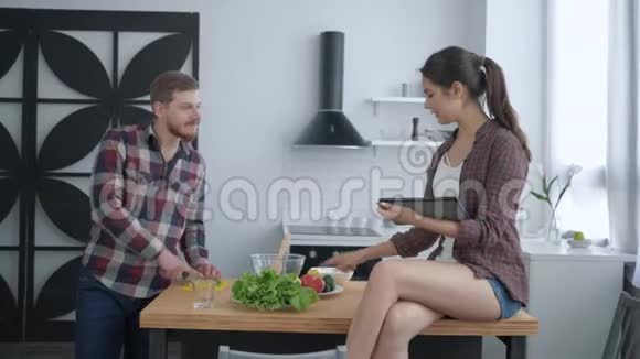 健康的饮食迷人的男性准备有用的素食晚餐和女性坐在厨房的桌子上视频的预览图
