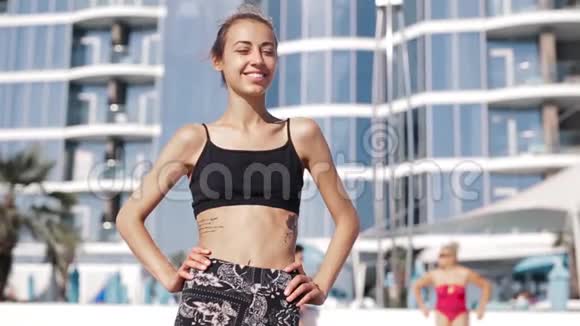 美丽苗条的年轻女子穿着运动服在海岸与水疗酒店快乐的女性性感的晒黑身体完美视频的预览图