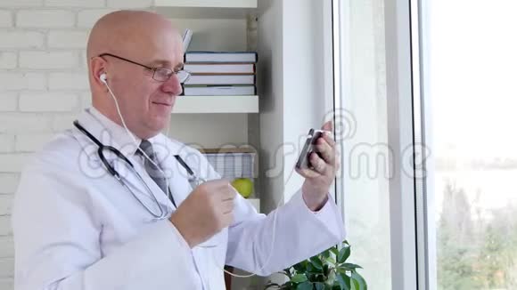 医生微笑及使用免提智能电话与病人交谈视频的预览图