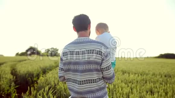 父亲把儿子扛在肩上日落时在麦田散步父亲节家庭观念视频的预览图