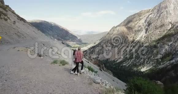 无人机飞过年轻的新婚夫妇站在一起在约塞米蒂国家公园观看惊人的风景山全景视频的预览图