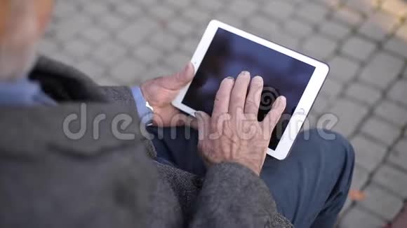 在外面用平板电脑把一个年长的男人锁起来坐在长凳上用平板电脑的老人的后景视频的预览图
