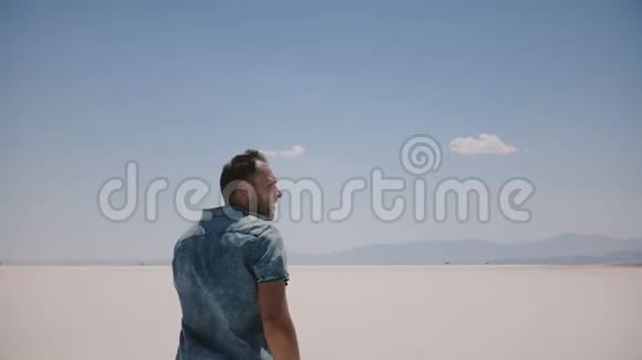 年轻快乐的自由人张开双臂在阳光明媚的盐漠湖自然风光中享受不可思议的公路旅行视频的预览图