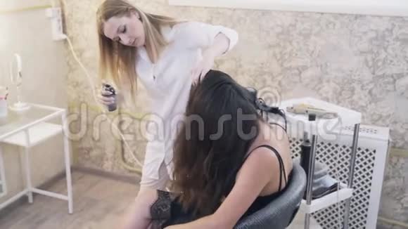 特写造型师使她美丽的客户头发洒头发与发胶修复造型和卷发概念视频的预览图