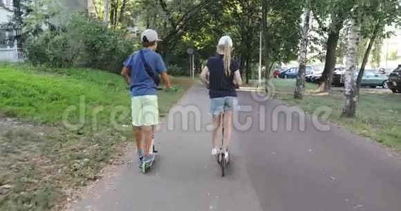 一个男孩和一个女孩在阳光明媚的天气里骑着滑板车在公园里聊天视频的预览图