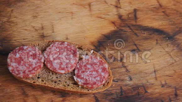 一个男人手拿一个三明治和肉片腊肠作为零食或早餐一片黑面包和一杯干面包视频的预览图